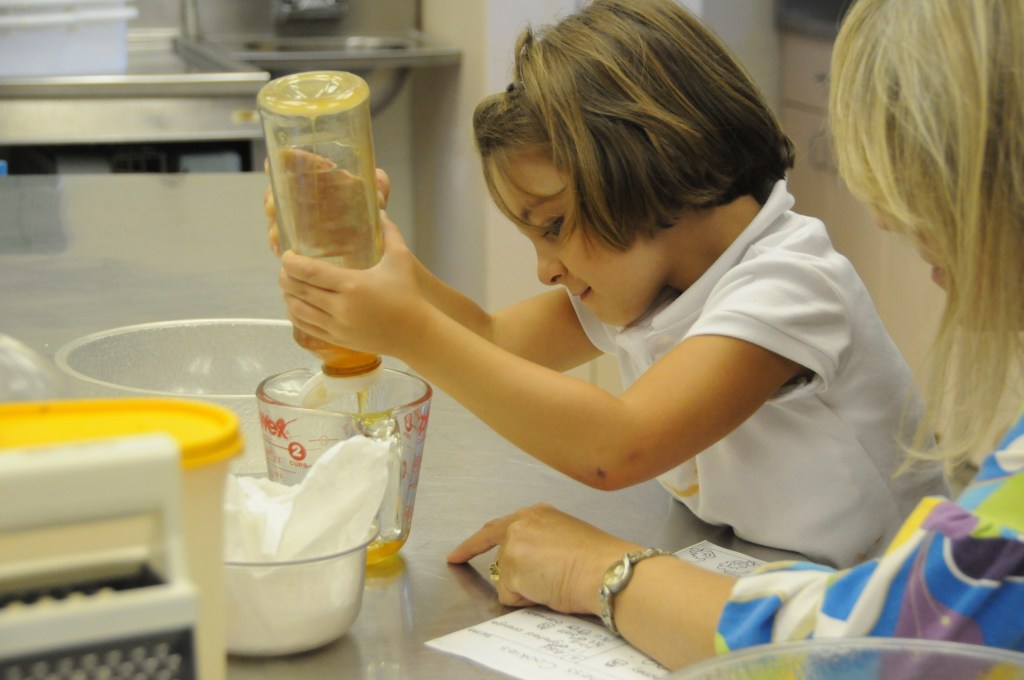 A Glenview New Church School kindergartener measures out honey with a measuring cup
